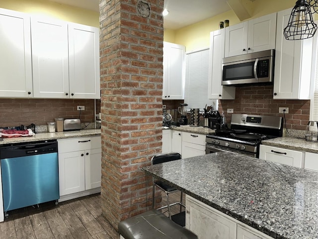 kitchen with stainless steel appliances, white cabinetry, dark wood finished floors, and decorative backsplash