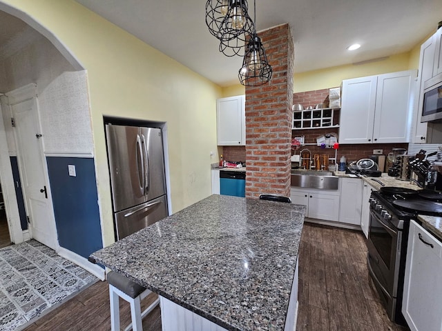 kitchen featuring dark wood-type flooring, arched walkways, stainless steel appliances, and a sink