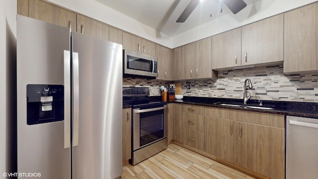 kitchen featuring stainless steel appliances, dark stone counters, a sink, and tasteful backsplash