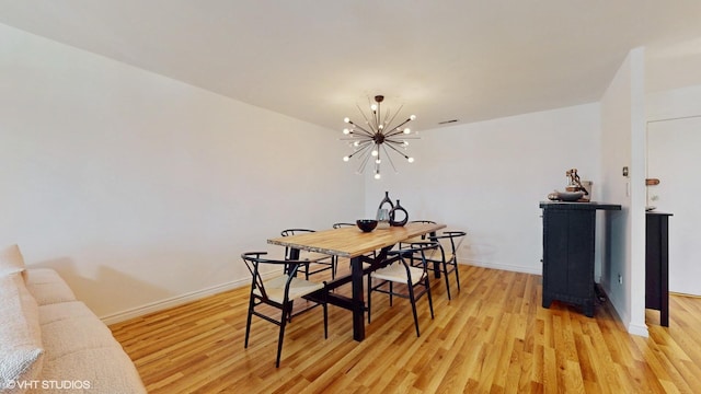 dining space with baseboards, a notable chandelier, visible vents, and light wood finished floors