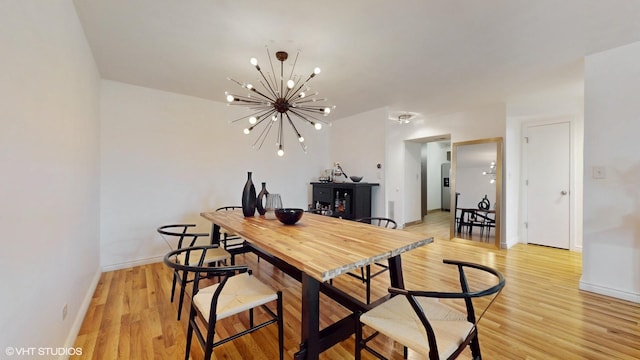 dining room with an inviting chandelier, baseboards, and light wood-style floors