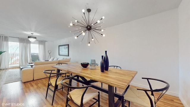 dining space with light wood-type flooring, baseboards, and a notable chandelier