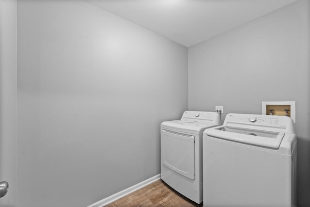 washroom with laundry area, baseboards, wood finished floors, and washing machine and clothes dryer