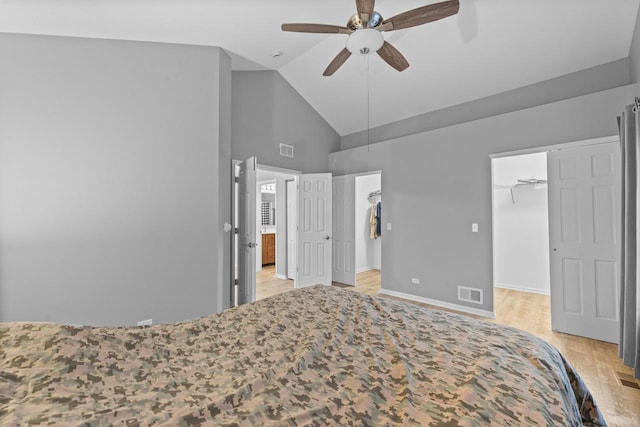 bedroom featuring light wood finished floors, visible vents, baseboards, ceiling fan, and a spacious closet