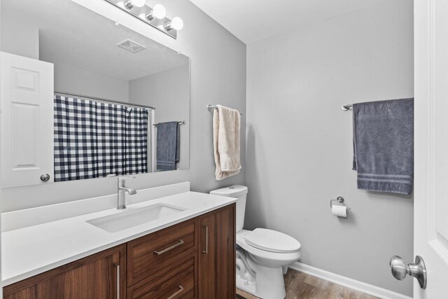 bathroom featuring toilet, wood finished floors, visible vents, vanity, and a shower with curtain