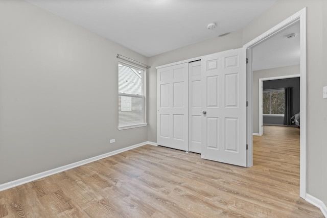 unfurnished bedroom with baseboards, a closet, and light wood-style floors