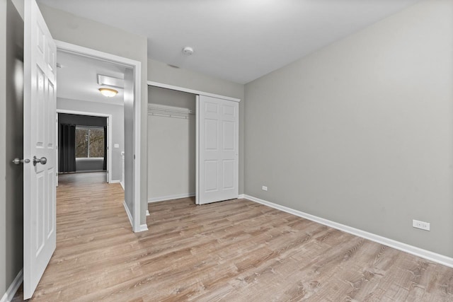 unfurnished bedroom with a closet, light wood-type flooring, and baseboards