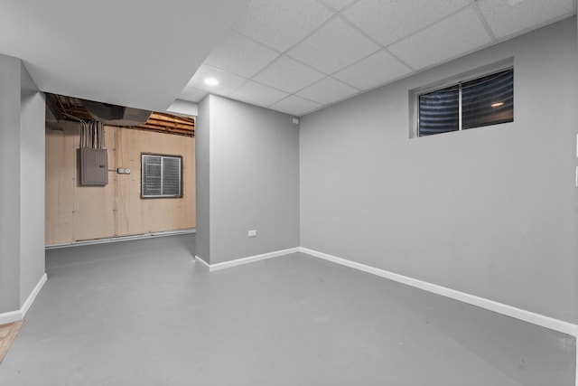 finished basement with electric panel, baseboards, and a drop ceiling