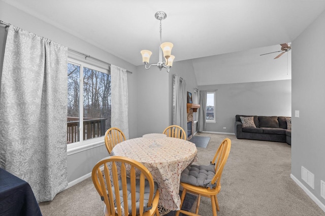 dining area featuring a fireplace with flush hearth, ceiling fan with notable chandelier, carpet flooring, and baseboards