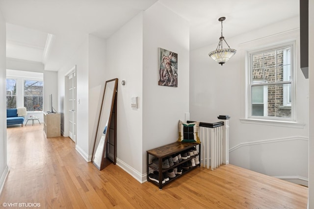 corridor featuring an upstairs landing, a healthy amount of sunlight, light wood-style flooring, and baseboards