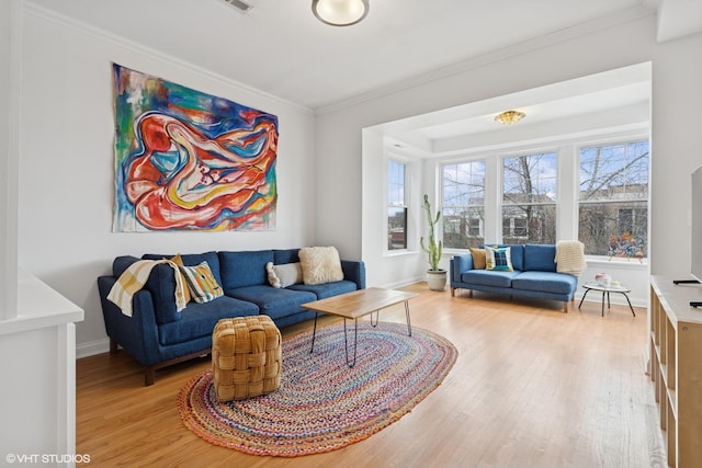 living area with light wood-style floors, baseboards, and crown molding