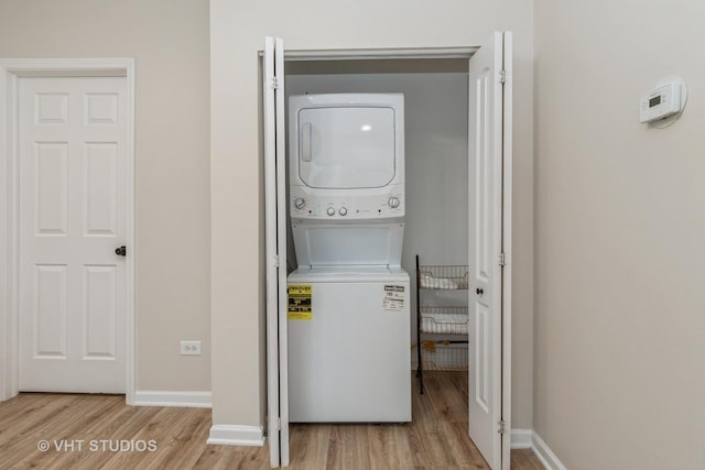 clothes washing area with laundry area, baseboards, stacked washing maching and dryer, and wood finished floors