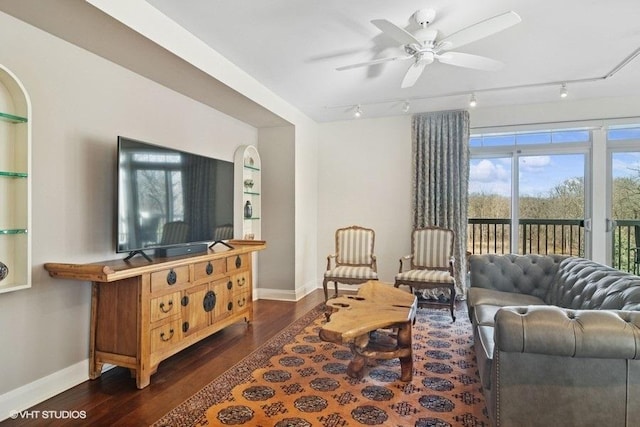 living room with dark wood-type flooring, track lighting, ceiling fan, and baseboards