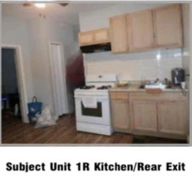 kitchen with light countertops, light brown cabinets, under cabinet range hood, and white gas range