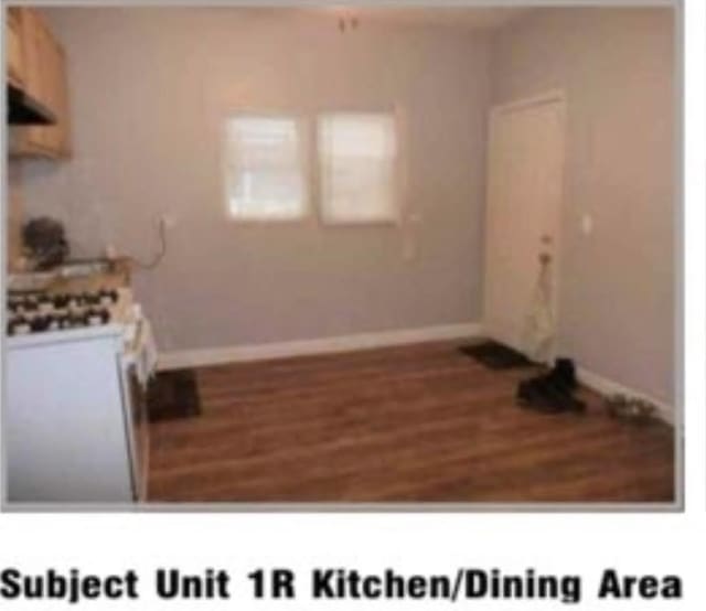 kitchen with white gas range, baseboards, and wood finished floors