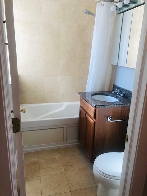 bathroom featuring toilet, tile patterned flooring, shower / bathtub combination with curtain, and vanity