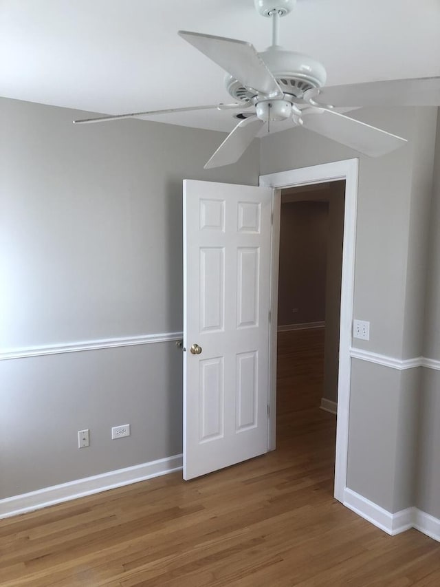 unfurnished bedroom featuring wood finished floors, a ceiling fan, and baseboards