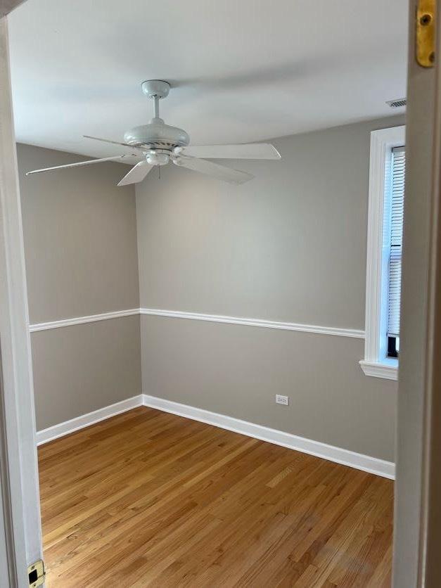 empty room featuring ceiling fan, baseboards, and wood finished floors