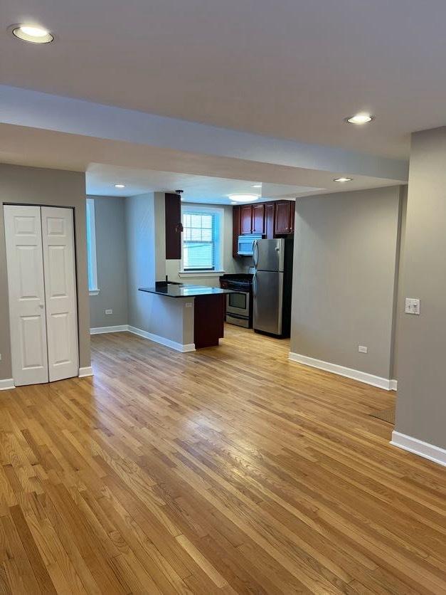 kitchen with appliances with stainless steel finishes, light wood-style flooring, and baseboards