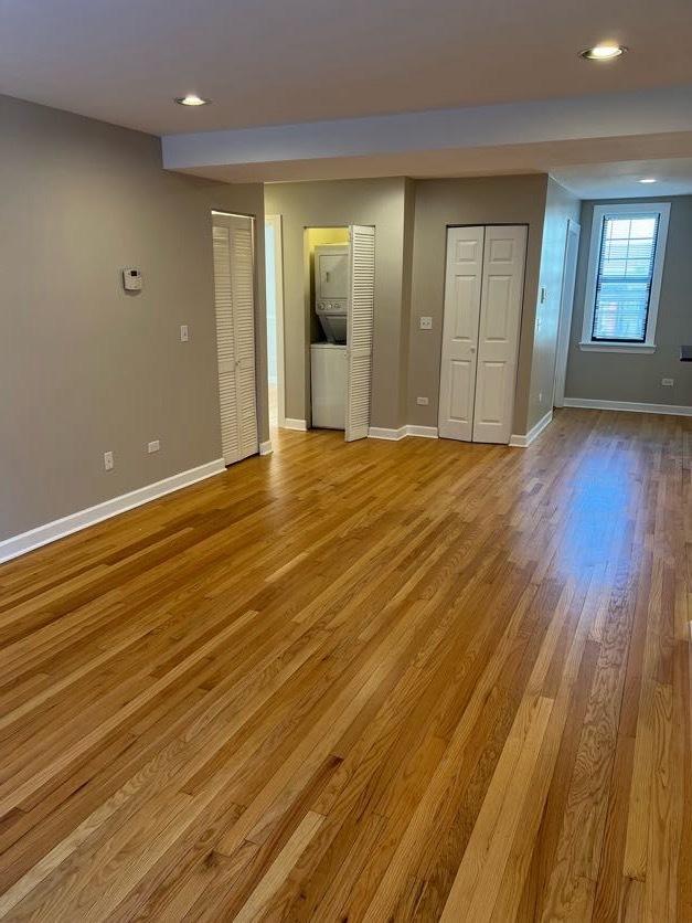 unfurnished bedroom with recessed lighting, light wood-style flooring, baseboards, and two closets