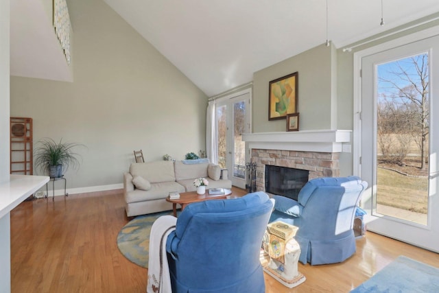 living area featuring wood finished floors, a fireplace, baseboards, and high vaulted ceiling