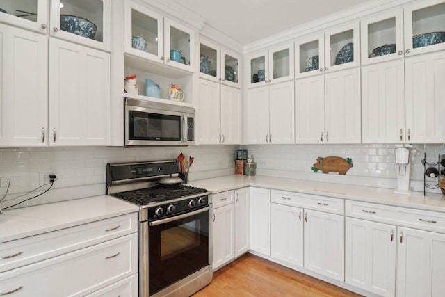 kitchen featuring light wood finished floors, appliances with stainless steel finishes, white cabinetry, and light countertops