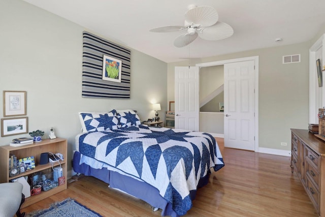 bedroom featuring visible vents, ceiling fan, baseboards, and wood finished floors