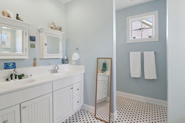 full bath featuring double vanity, baseboards, and a sink