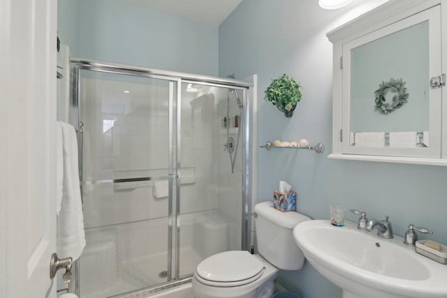 bathroom featuring a sink, toilet, and a stall shower