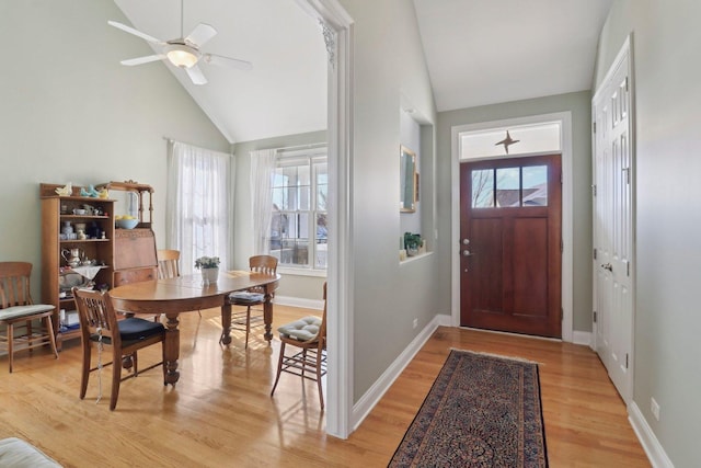 entryway with high vaulted ceiling, baseboards, light wood-style floors, and a ceiling fan