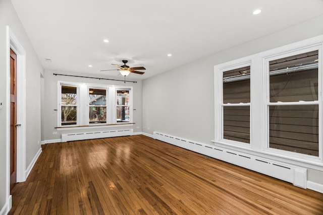 empty room with recessed lighting, wood-type flooring, and baseboard heating