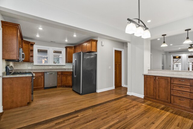 kitchen with stainless steel appliances, dark wood-style flooring, baseboards, backsplash, and brown cabinetry