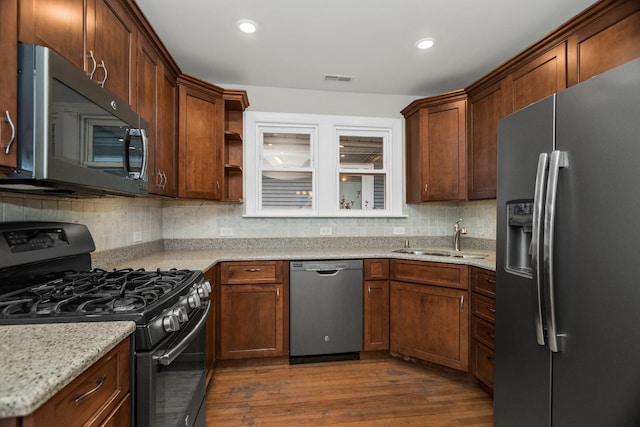 kitchen featuring decorative backsplash, dark wood finished floors, appliances with stainless steel finishes, a sink, and recessed lighting