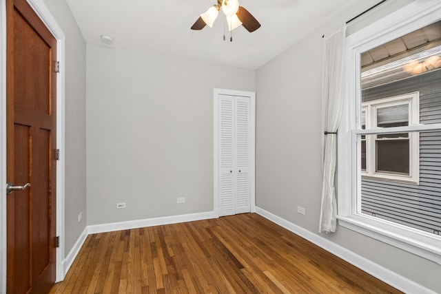 unfurnished bedroom with hardwood / wood-style flooring, a ceiling fan, baseboards, and a closet