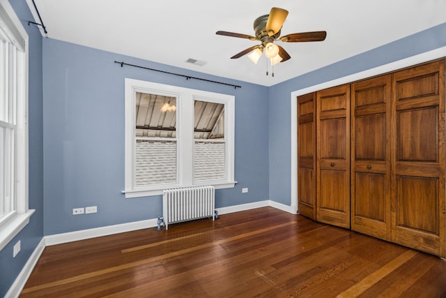 unfurnished bedroom featuring dark wood-type flooring, radiator heating unit, visible vents, and baseboards