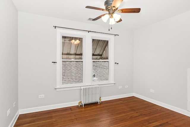 empty room featuring baseboards, hardwood / wood-style floors, a ceiling fan, and radiator