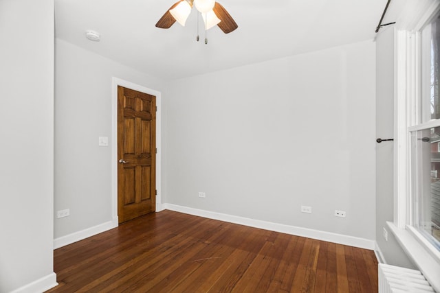 unfurnished room featuring a ceiling fan, radiator, dark wood finished floors, and baseboards