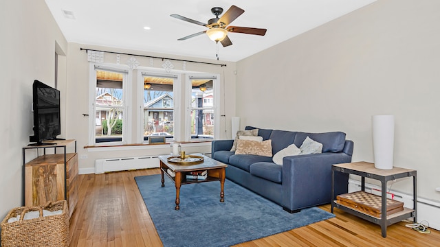 living room featuring visible vents, baseboard heating, hardwood / wood-style flooring, and a ceiling fan