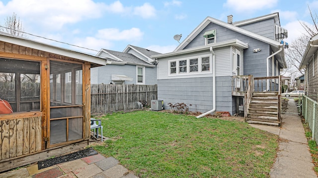 exterior space with a lawn, a sunroom, a fenced backyard, a chimney, and central air condition unit