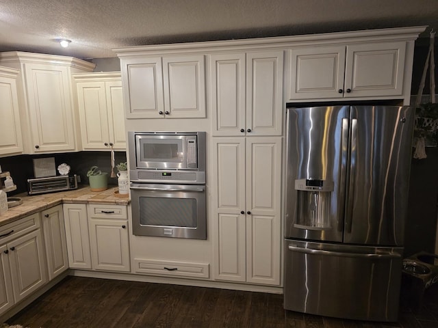 kitchen featuring appliances with stainless steel finishes, white cabinets, dark wood-type flooring, and a textured ceiling