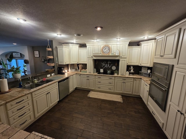 kitchen featuring dark wood-style flooring, stainless steel dishwasher, wall oven, a sink, and black microwave