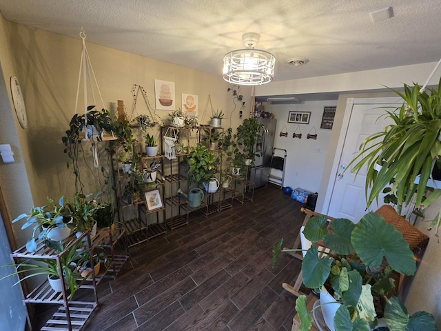 interior space featuring a notable chandelier, visible vents, a textured ceiling, and wood finish floors