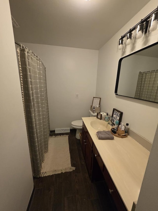 bathroom featuring baseboards, toilet, a shower with curtain, wood finished floors, and vanity