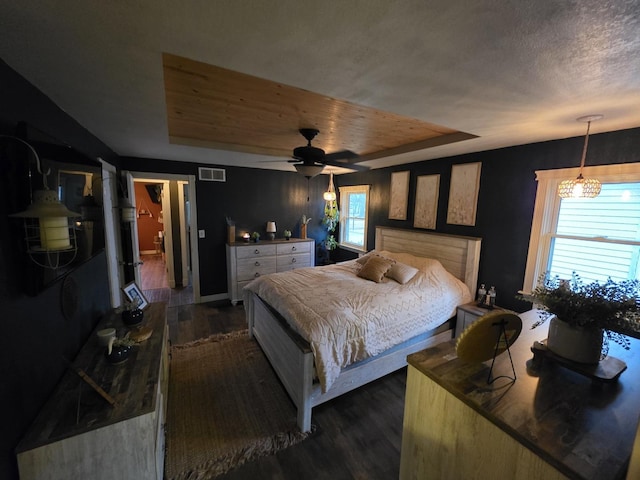 bedroom with dark wood-style floors, visible vents, and a raised ceiling