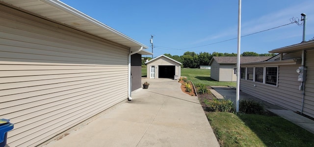 view of side of home featuring a garage, a yard, a patio area, and an outdoor structure