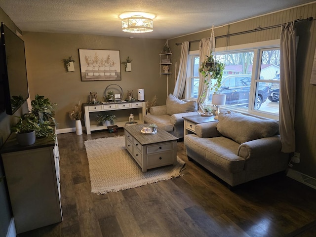 living room with dark wood-type flooring, a textured ceiling, and baseboards