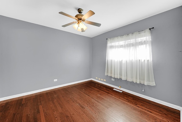 unfurnished room with dark wood-style floors, a ceiling fan, visible vents, and baseboards