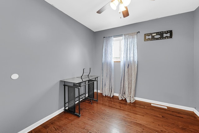 empty room featuring ceiling fan, baseboards, and wood finished floors