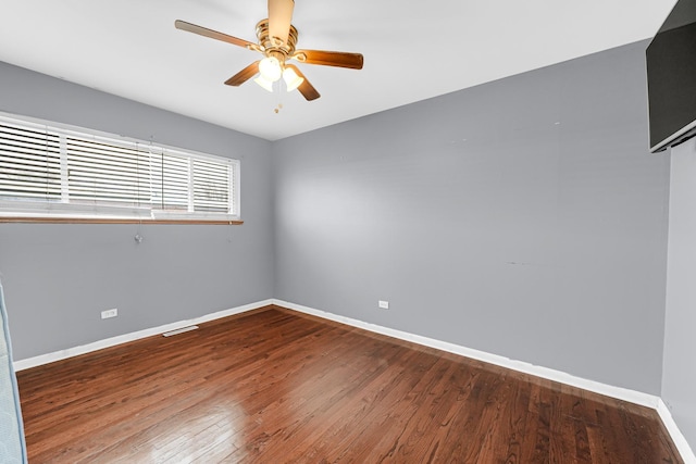 empty room featuring wood finished floors, a ceiling fan, and baseboards