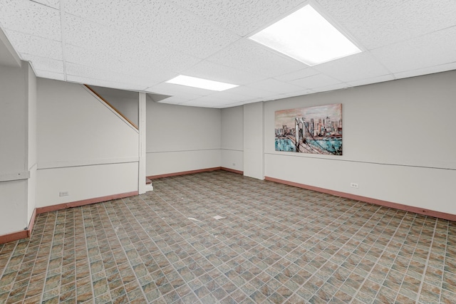 finished basement featuring a paneled ceiling and baseboards